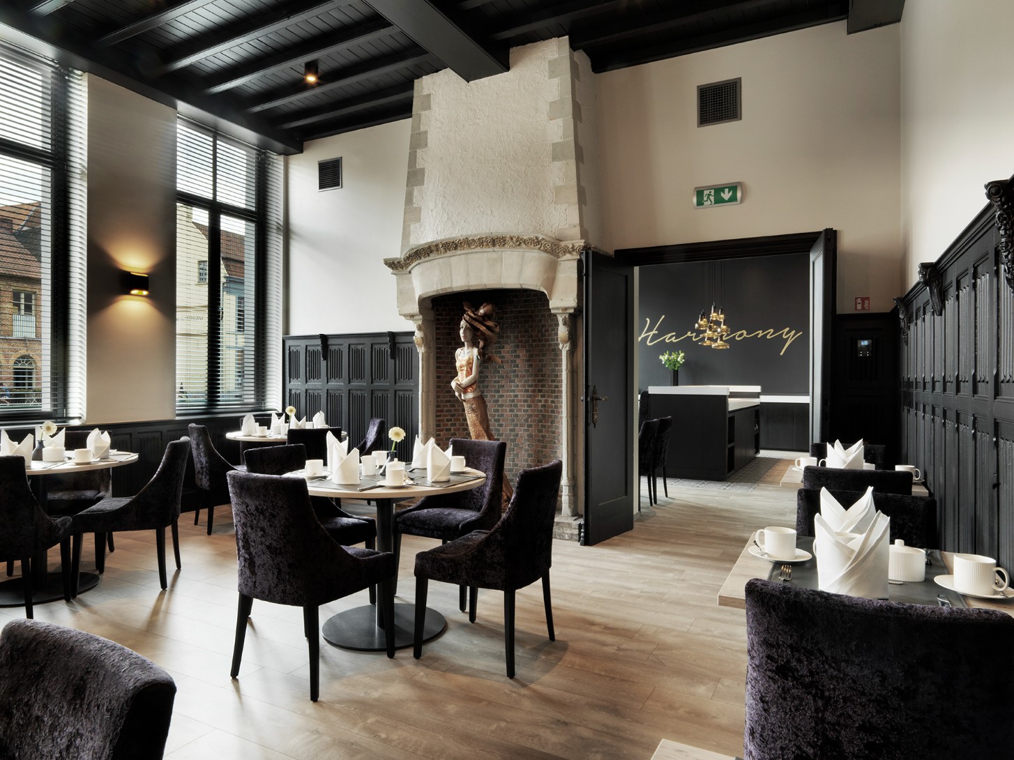 Fine dining restaurant met ontvangstruimte, sculpturale open haard, elegante zwarte meubels en decoratie.